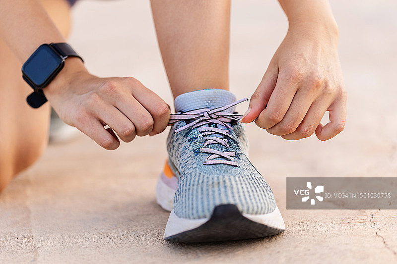 女性慢跑者在跑步前系鞋带的特写镜头。动力，健康的生活方式和健身理念。图片素材
