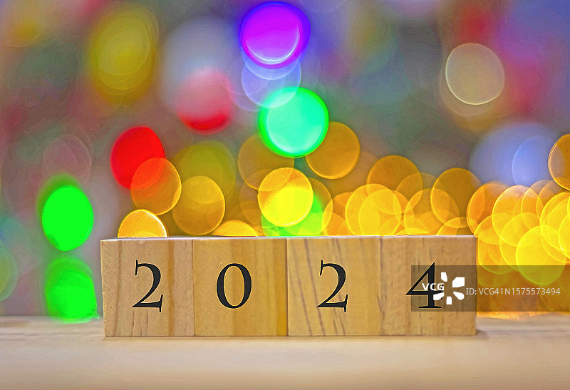 数字“2024”在玩具木块照亮散焦圣诞灯的背景图片素材