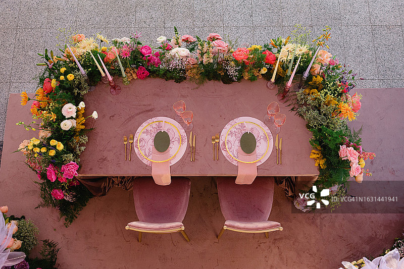 餐桌上摆放着为新婚夫妇准备的金色餐具、鲜花和时髦的粉色眼镜图片素材