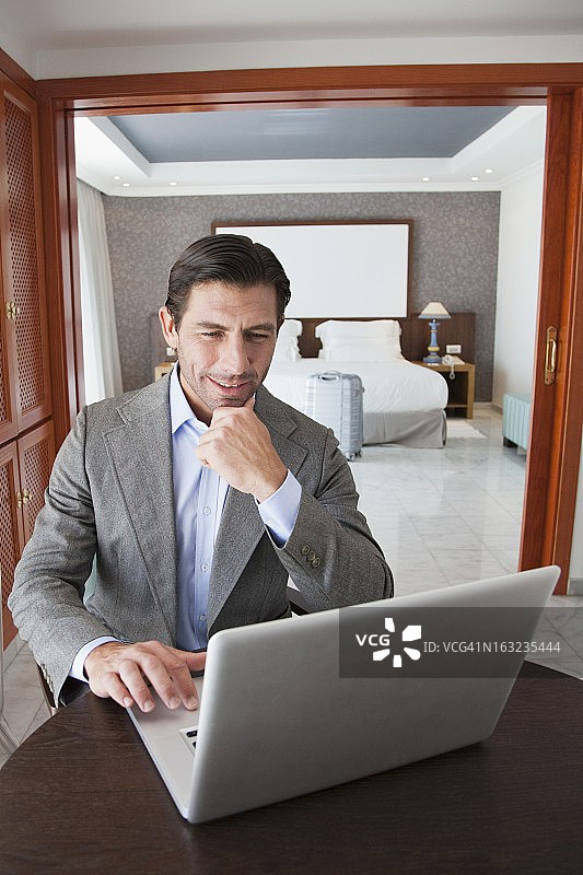 在酒店房间使用笔记本电脑的商人图片素材