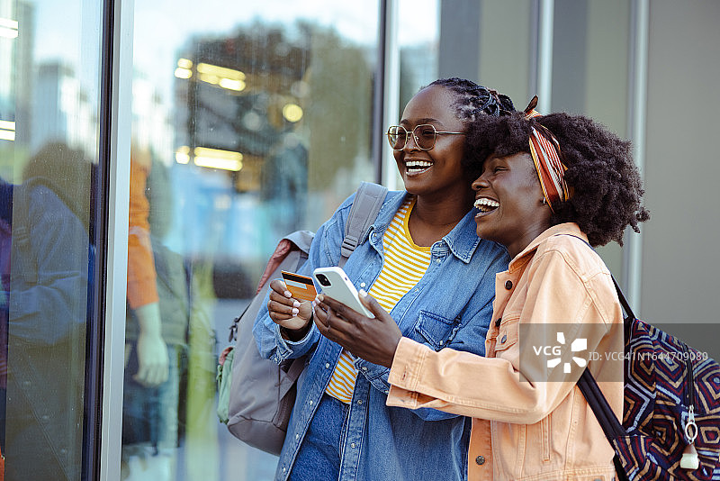 非裔美国女性朋友在智能手机上使用网上银行服务，看着商店橱窗图片素材