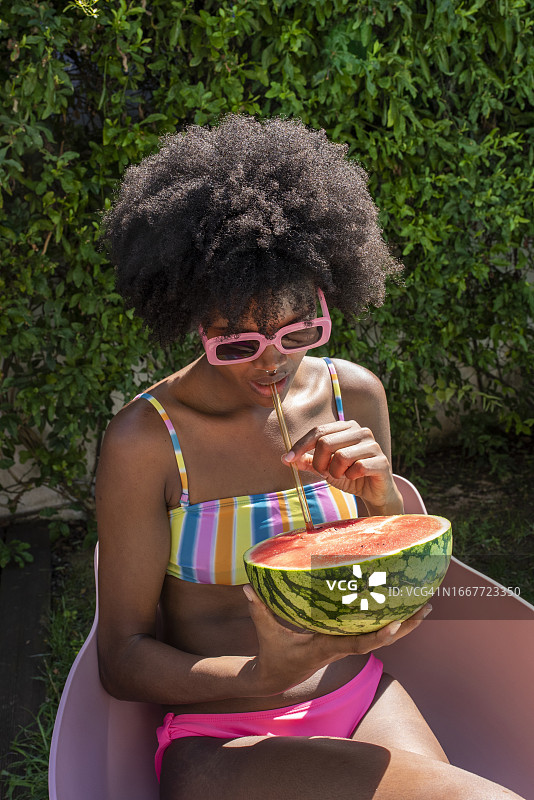年轻女子在晴天用吸管喝西瓜汁图片素材