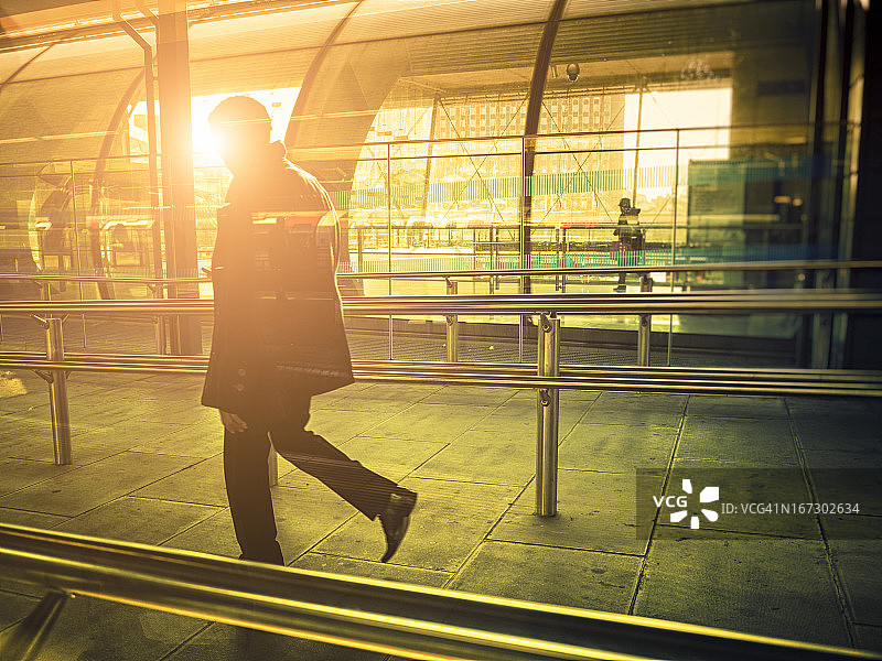 伦敦，商人走在阳光下的现代车站里图片素材