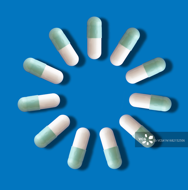 药物以胶囊的形式呈现在蓝色背景和一个小阴影上。图片素材