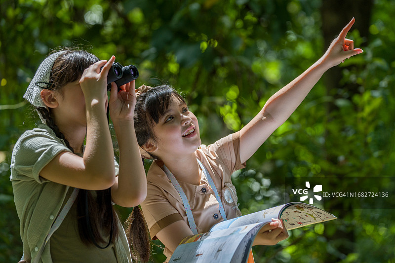 树林里的女学生拿着双筒望远镜。图片素材