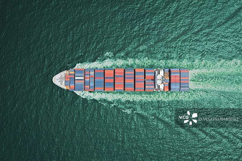 航拍俯视图集装箱货船以美丽的波浪图案全速运载集装箱在海上进行商业物流、进出口、海运或货物运输。图片素材