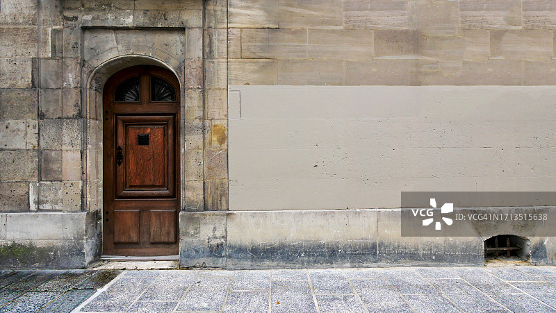 法国巴黎，古老的棕色和彩绘的石头立面，木门和灰色的石头人行道图片素材