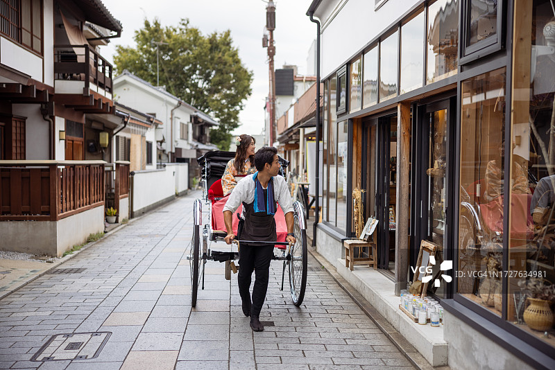 独自旅行的女人穿着和服/ Hakama骑人力车在传统的日本小镇图片素材