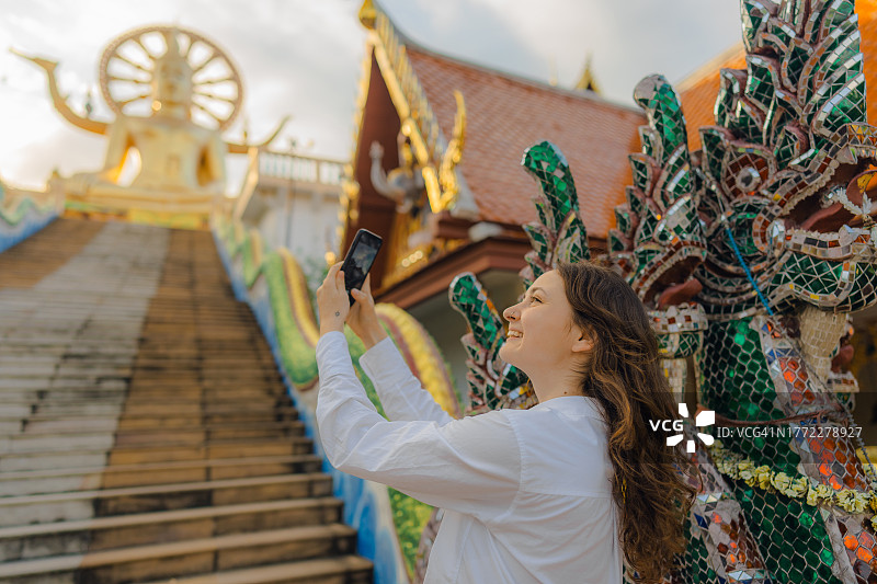 在苏梅岛大佛寺用智能手机拍照的女子图片素材