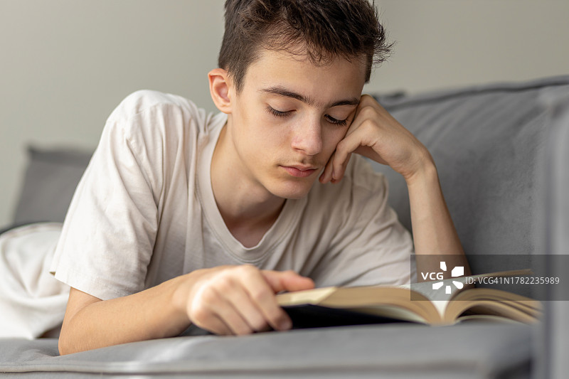 年轻人躺在家里的床上看书图片素材
