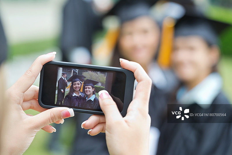 智能手机与毕业生合影的特写图片素材