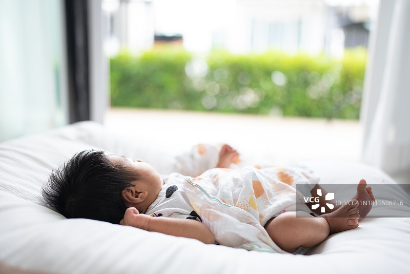 亚洲女婴躺在床上，看着风景图片素材