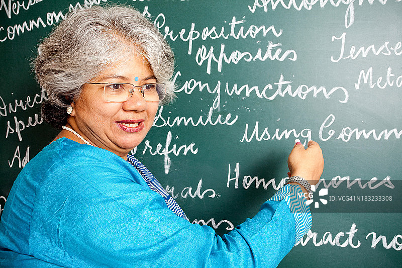欢快的印度亚裔女英语老师在教室与greenboard图片素材