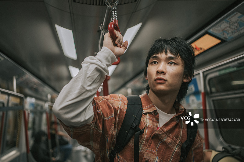 站在地铁里旅行的亚洲年轻人图片素材