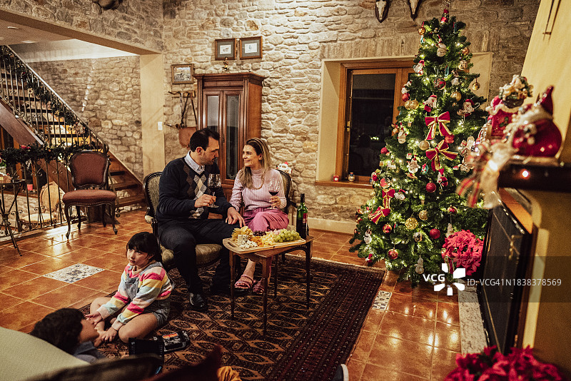 圣诞节的时候，父母在家里喝着酒，孩子们在壁炉旁放松图片素材