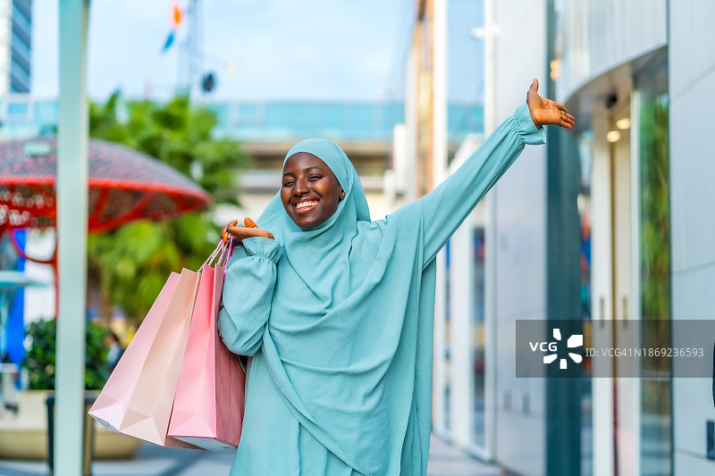 一名穆斯林妇女在城里快乐地购物图片素材