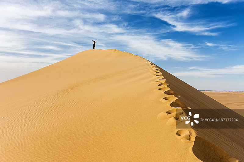 女游客站在撒哈拉沙漠的沙丘顶部图片素材