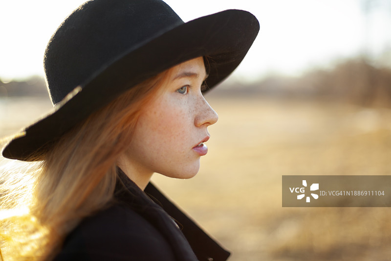 阳光明媚的日子里，戴着帽子的年轻女子的肖像图片素材