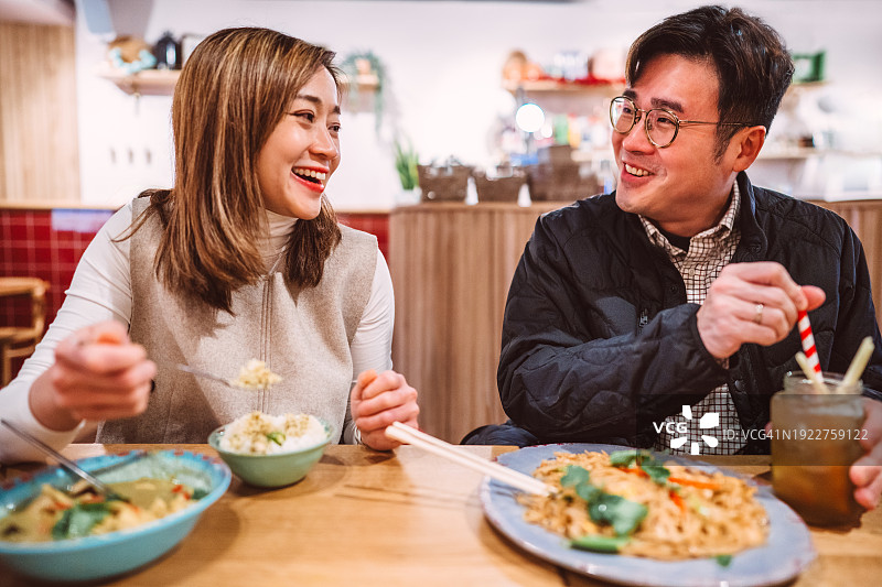 一对快乐的亚洲夫妇在餐厅里一起享受美食图片素材