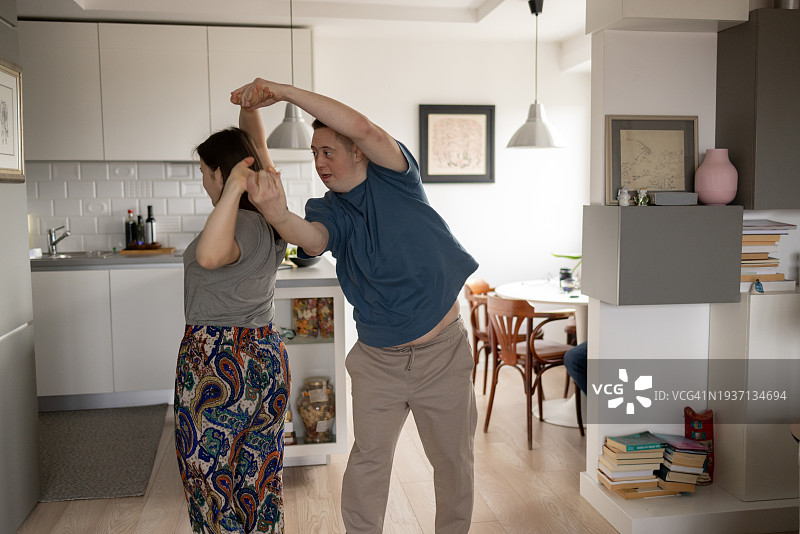 患有唐氏综合症的年轻夫妇在客厅跳舞。图片素材