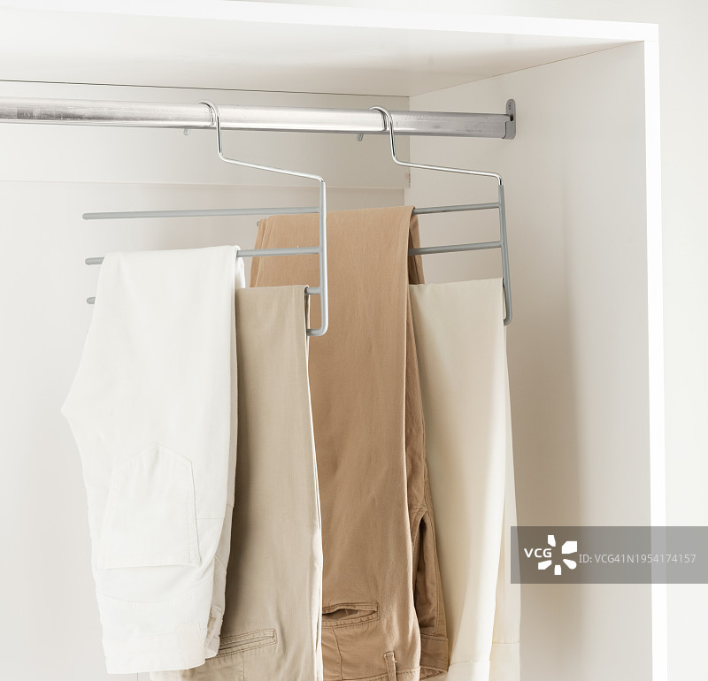 采购产品衣橱与衣架，衣服挂在不锈钢衣架在现代，明亮，白色的更衣室。图片素材