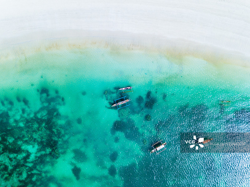 龙目岛白色沙滩附近绿松石水上的船只鸟瞰图。图片素材