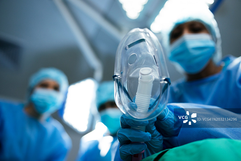 低角度，外科医生和氧气面罩用于手术室手术，医生和麻醉用pov。透视，医疗程序和气体设备，治疗和人员在剧院的健康图片素材