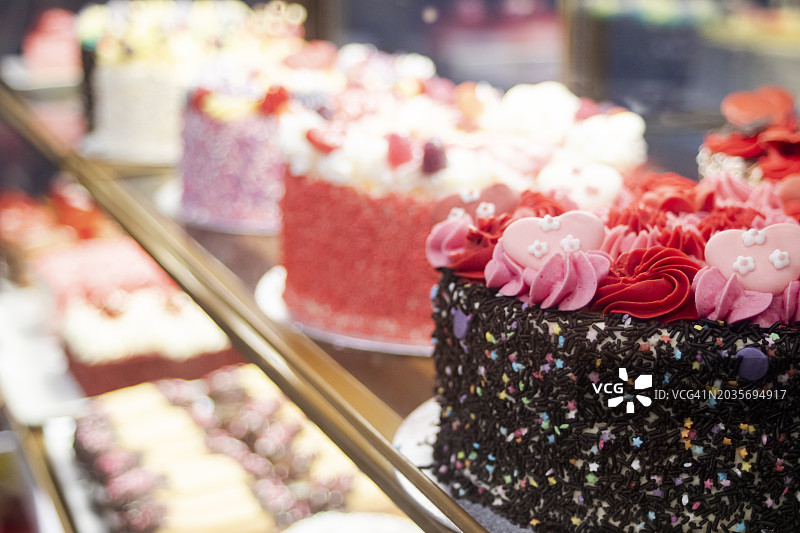 粉红色和红色糖霜的漂亮蛋糕陈列在咖啡馆冰箱出售，近距离观看图片素材