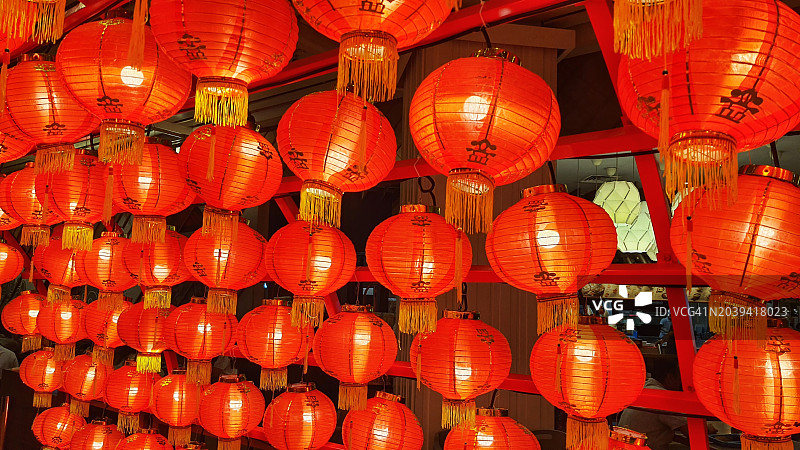 一串红色的中国灯笼，装饰着金色的流苏，上面写着吉祥的中国书法。图片素材