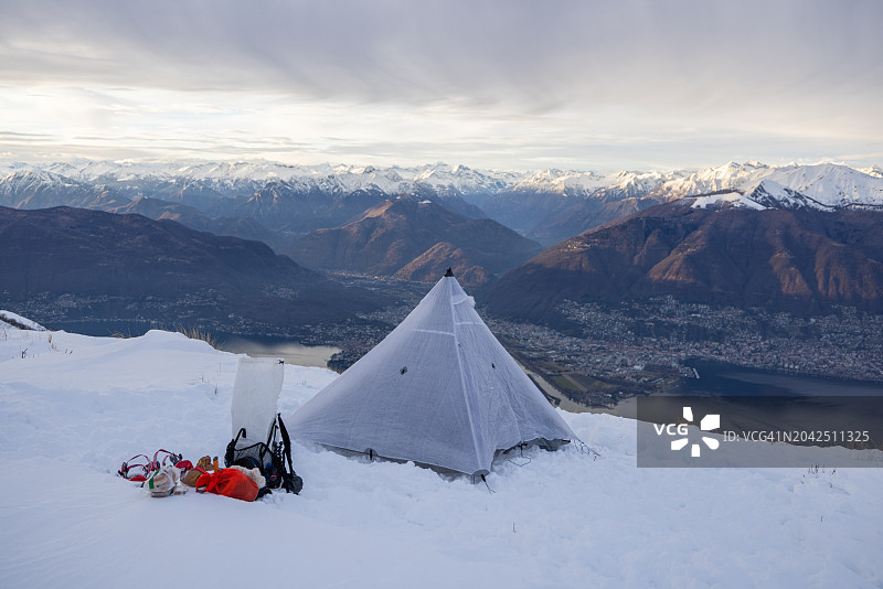 在雪地里露营，帐篷是建在一个湖、山脉之上的高峰上图片素材