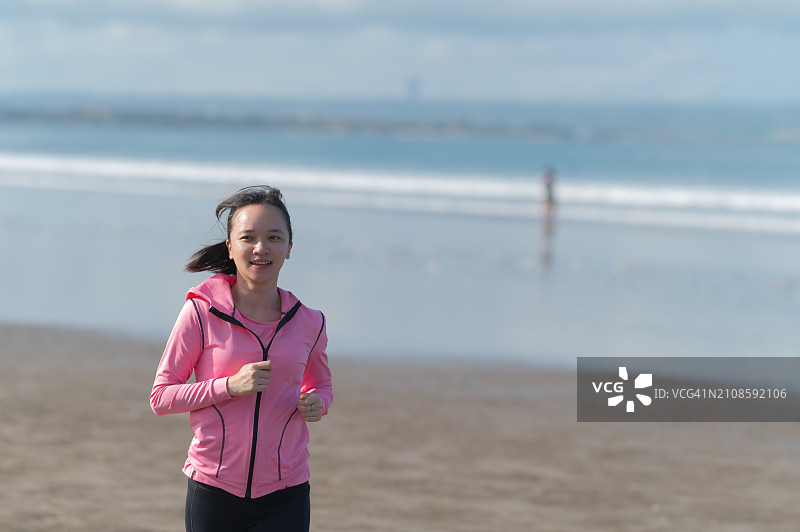 亚洲女性在海滩慢跑图片素材