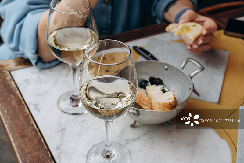 一名妇女在当地餐馆或小卖部喝开胃白葡萄酒，配上传统的意大利开胃菜新鲜面包和橄榄图片素材
