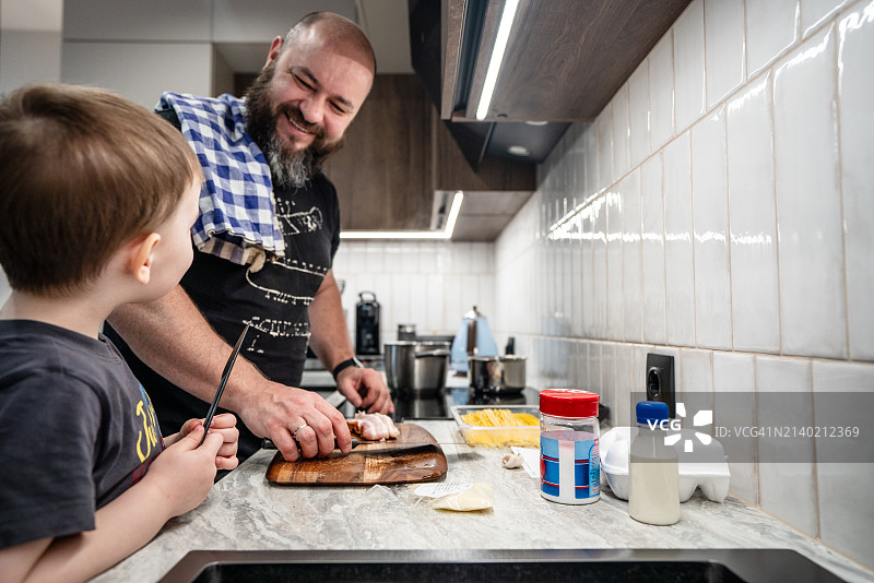 快乐的父亲和儿子一起在厨房做饭图片素材