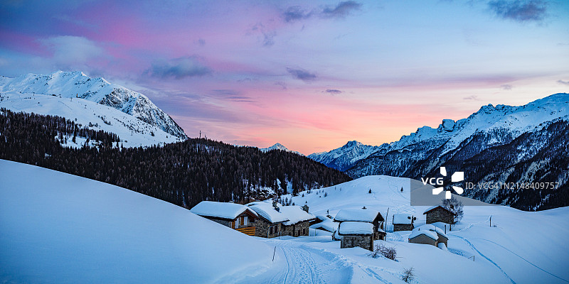 粉红色夕阳下的雪山和小屋图片素材