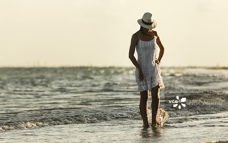 美丽的女人穿着白色漫步在荒芜的海滩图片素材