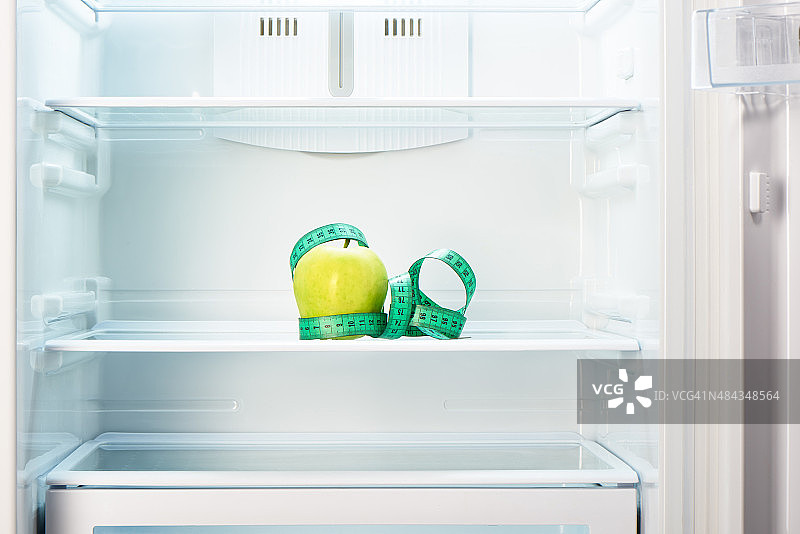 空冰箱架子上的青苹果和卷尺图片素材