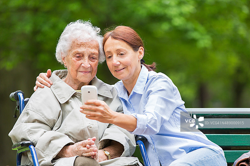 坐在轮椅上的老年妇女和户外的家庭护理员图片素材