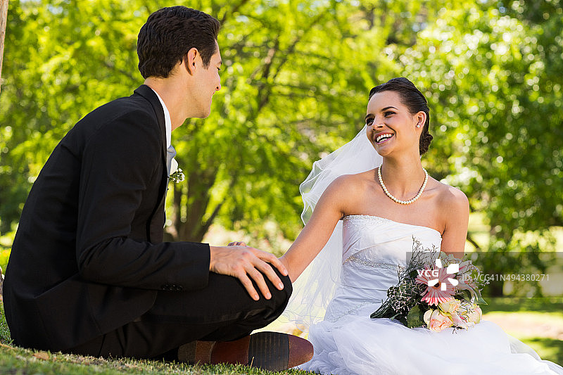 快乐的新婚夫妇坐在公园里图片素材