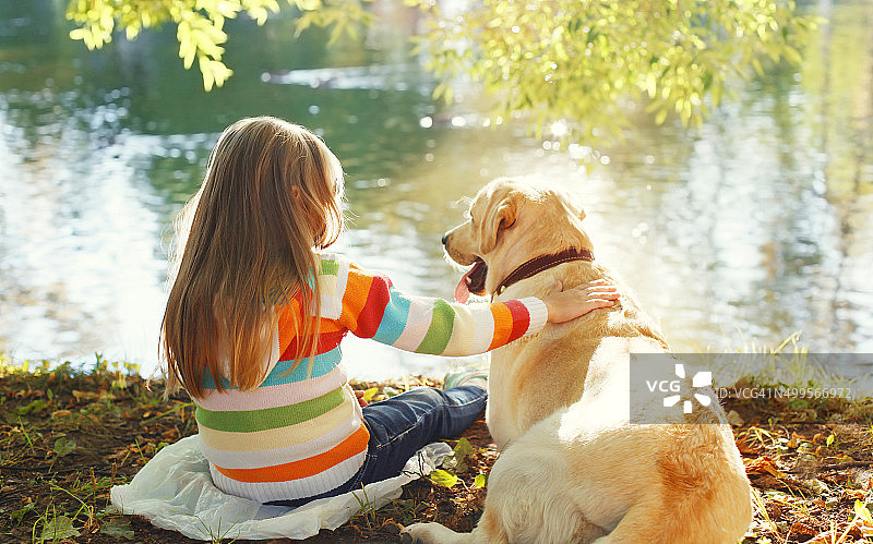 两个朋友，孩子和拉布拉多猎犬坐在阳光下图片素材
