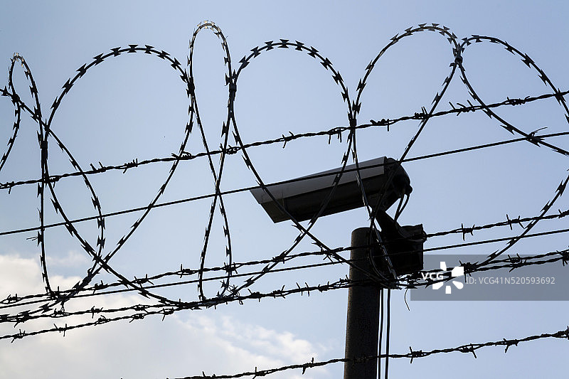 监狱围墙周围的铁丝网后面有监控摄像头图片素材