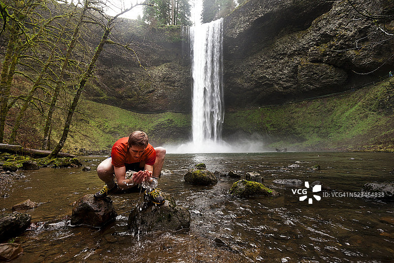 美国俄勒冈州塞勒姆，一名男子在瀑布附近往脸上泼水图片素材