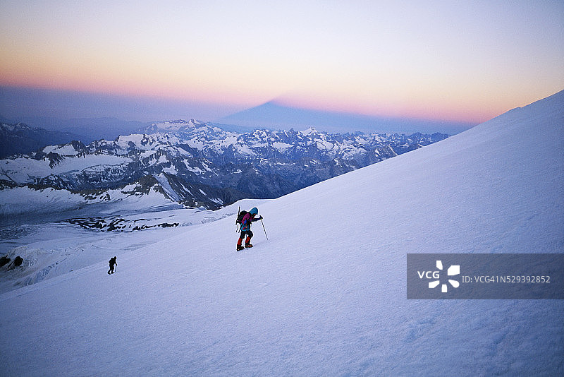 在日出时攀登白雪覆盖的山图片素材