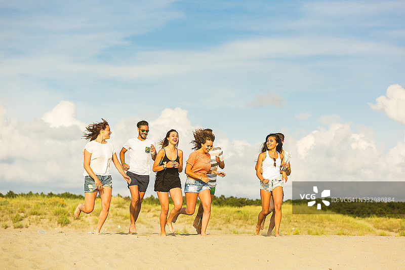 一群在海滩上跑步的多种族朋友图片素材