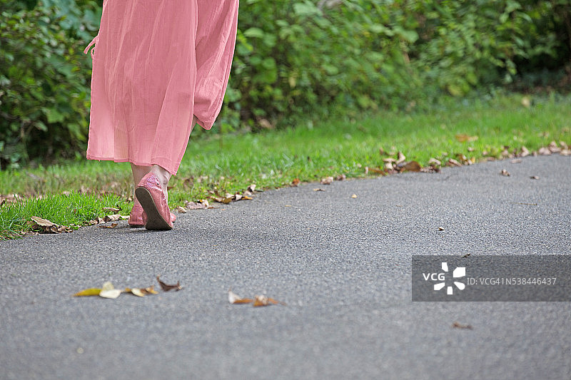 穿浅粉色衣服的女人独自走着图片素材