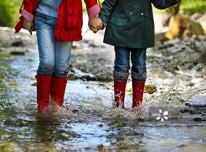 孩子穿着雨靴跳。近距离图片素材