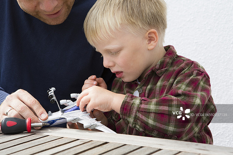 中年成年男子和儿子在院子桌子上准备玩具飞机图片素材