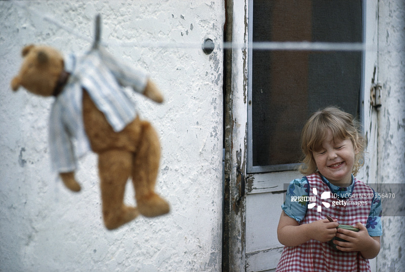 晾衣绳上的泰迪熊和笑着的女孩图片素材