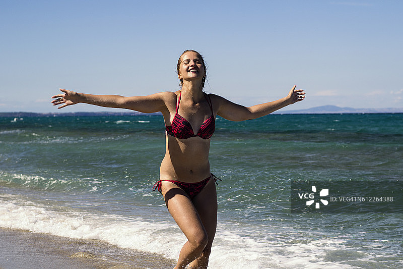 快乐的年轻女子在沙滩上玩耍奔跑图片素材