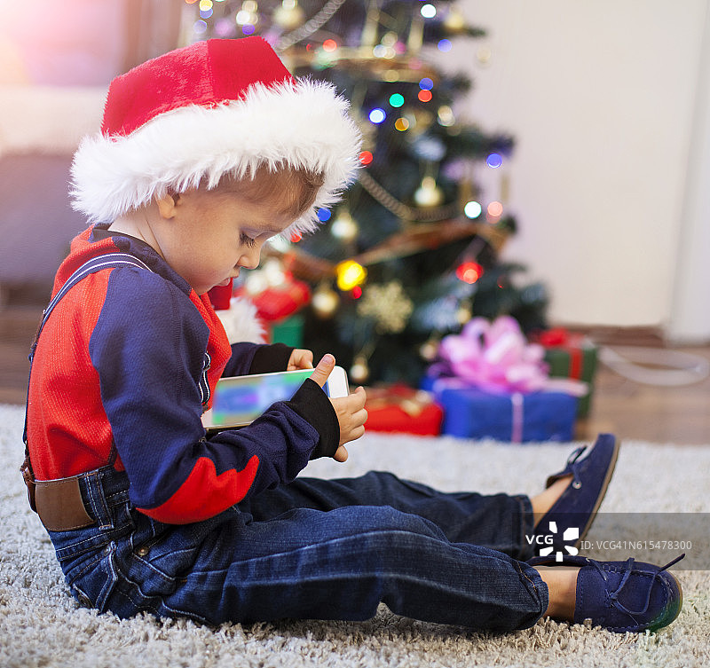 婴儿在圣诞老人的帽子和圣诞礼物-智能手机图片素材