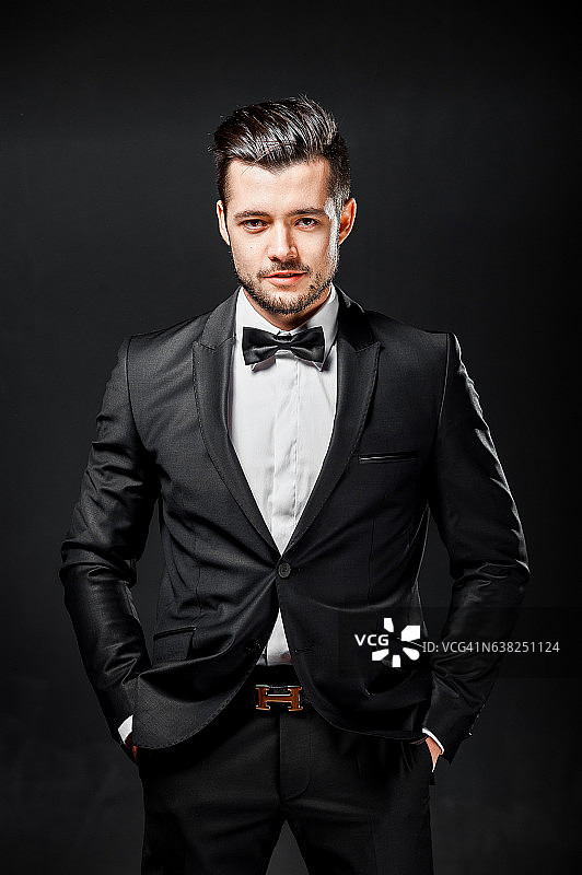 自信英俊的男人的肖像穿着黑色西装和领结图片素材